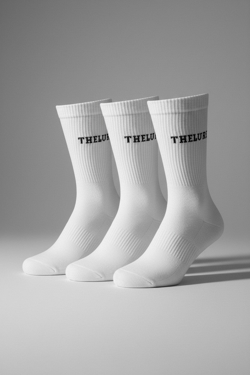 Drei weisse thelureclothing Performance-Socken mit schwarzem Logo-Schriftzug und rutschfester Grip-Sohle.